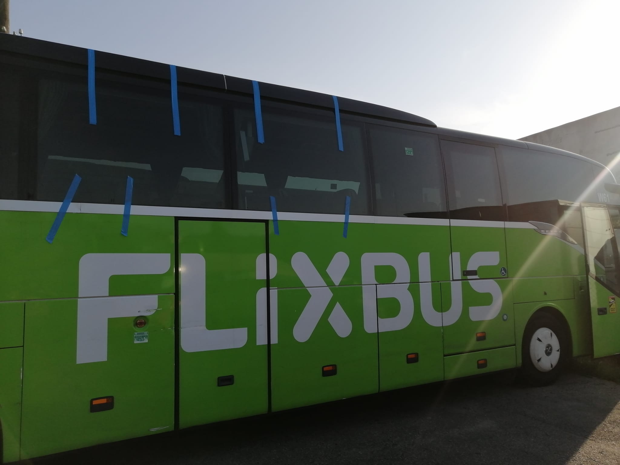 Side windows of a green coach, showing the sequence of panes and blue tape at several edges.